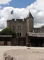 Photographie en couleurs d'un ensemble de bâtiments dont une tour cylindrique à l'aspect médiéval.