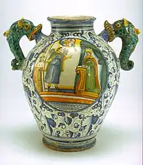 Vase ovoïde à anses en forme d'hippocampes ; l'Annonciation est peinte sur une face au centre d'un médaillon, de l'autre côté un cartouche médicinal, Montelupo Fiorentino, XVIe – XVIIe&nbsp;siècle.