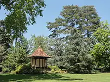 Au milieu d'arbres, petit bâtiment à colonne, couvert d'un toit aux tuiles teintées formant un dessin géométrique.