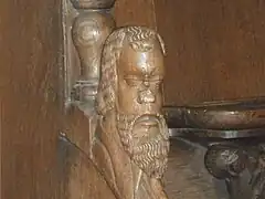 Tête sculptée sur l'accoudoir en bois séparant deux stalles.