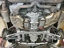 Vue par le dessous du train arrière LSA. On voit au premier plan le carter ainsi que les échappements du moteur. Le train arrière est légèrement en retrait du moteur et sous la boîte de vitesses.