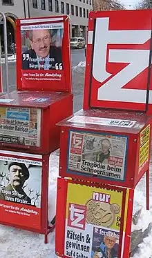 deux présentoirs à journaux rouges dans une rue