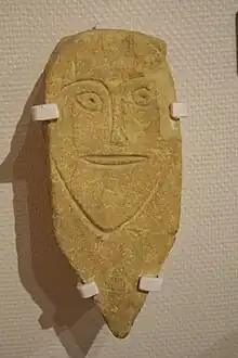 Stèle de pierre taillée en biseau et présentant un visage stylisé