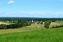 Photographie en couleurs de la rue principale d'un village et d'un lotissement.