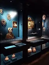 Vitrine exposant des céramiques espagnoles, des figures pieuses, des monnaies ibériques diverses.