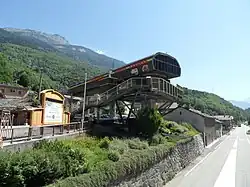 Photographie de la gare de départ de la télécabine 3 Vallées Express dans son ancienne version originelle au-dessus de la route, le toit a des lettres qui sont celles de l'appellation de la télécabine.