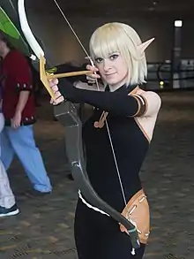 Cosplay d'Evangelyne, en habit moulant noir, cheveux blonds et oreilles pointues.