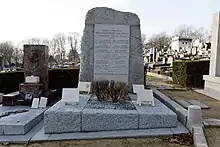 Tombe avec en tête grande stèle portant plaque sur laquelle est gravé : « Gloire à nos élus héros et martyrs de la Résistance assassinés par les nazis ». Au-dessous, 11 noms, dont celui de Corentin Cariou. En bas : « Ils sont morts pour que vive la France !