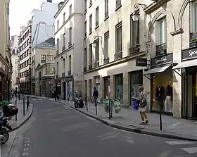 Rue plutôt étroite d’un quartier historique de Paris, avec quelques commerces.