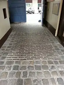 Les pavés en bois visibles dans les rectangles centraux sous le porche du passage.