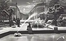photographie en noir et blanc d'une fontaine et d'une statue, avec des montagnes en arrière plan.