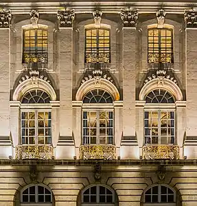 Effets de lumières sur un mur ouvragé percé d'ouvertures vers des pièces éclairées.