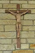 Sur un mur de pierre, bois peint représentant Jésus en croix.