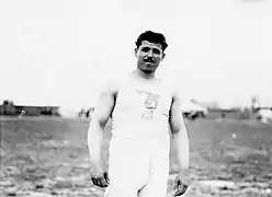 Portrait d'un homme à moustache portant une tunique illustrant une statue d'un athlète lançant un disque