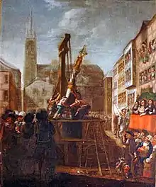 Des ouvriers sur un échafaudage en bois dressent une colonne de pierre sous le regard des badauds