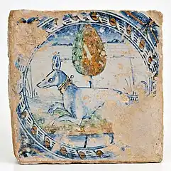 Carreau avec chien accroupi inséré dans une guirlande circulaire, période de César Borgia (1499&nbsp;– 1503), église Santa Maria del Riposo, connue sous le nom dei Piattelletti, à Fano, Pesaro, fin XVe&nbsp;siècle.