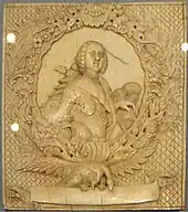 Morceau d'ivoire avec de riches gravures, représentant un monarque au centre d'un cadre ovale décoré.