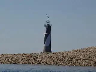 Vue d’un phare en arrière-plan d’une plage, le corps blanc et noir.