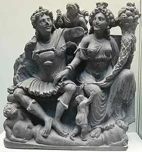 Le couple protecteur Panchika et Hariti (à la corne d'abondance): réminiscence classique (méditerranéenne antique) IIe – IIIe&nbsp;siècle. Schiste. British Museum, provenance Takht-i-Bahi
