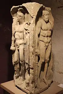 Vu d'un fragment de pilier antique parallélépipédique avec une statue en bas-relief sur chaque face.