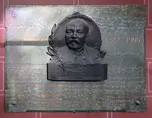 plaque en marbre vert sur laquelle est apposé le portrait en bronze de Lenoir ; en lettres dorées figure l’inscription suivante : Étienne Lenoir (portrait) 1822 - 1900 Inventer du premier moteur à gaz industriel 1860 Plaque commémorative érigée par souscription sur l'initiative de la Chambre Syndicale de l’Industrie des moteurs à gaz, à pétrole et des gazogènes le 16 décembre 1912 Monsieur Fernand David, ministre du commerce et de l’Industrie (J. Malet)