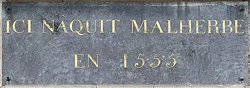 Plaque sur la façade de sa maison natale à Caen.