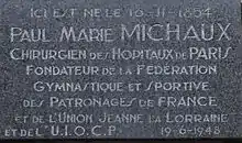Photo de la plaque commémorative apposée sur la maison natale de Paul Michaux avec, pour inscription : « Ici est né le 16-11-1854 Paul Marie Michaux, Chirurgien des Hôpitaux de Paris Fondateur de la Fédération Gymnastique et Sportive des Patronages de France et de l’Union Jeanne la Lorraine et de l’U.I.O.C.P 19-6-1948 ».