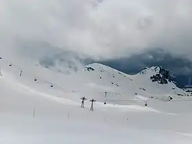 La pointe du Tougne au centre et le roc des Blanchets à droite depuis la roche de Mio au nord-est avec à leurs pieds le télésiège de Carellaz et la télécabine de la Roche de Mio.