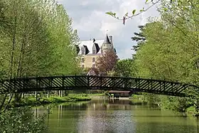 Photographie en couleurs d'une passerelle métallique enjambant un cours d'eau.