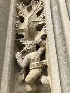 Sculpture d'un petit homme escaladant une feuille de vigne.