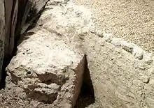 Vue d'une portion de mur arasé se raccordant à un autre mur courbe