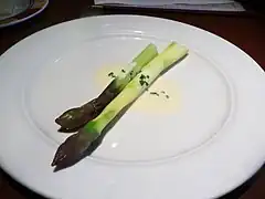Deux asperges produites à Lauris, dans le Vaucluse, présentées sur la même assiette avec une sauce au beurre blanc