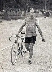 Photographie en noir et blanc d'un cycliste marchant à côté de son vélo.