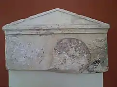 Haut de la stèle à fronton et antéfixes représentant la tête d'un jeune homme (A1026). Marbre de Paros, fin du Ve&nbsp;siècle&nbsp;av. J.-C.