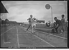 Photographie en noir et blanc d'un homme en tenue foncée de l'équipe de France portant le dossard no&nbsp;22. Il s'agit de René Wiriath. Il devance un homme en tenue blanche, représentant l'équipe d'Allemagne, portant le dossard no&nbsp;15