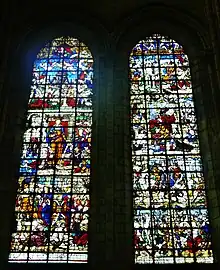 Deux grandes verrières colorées avec de nombreux personnages et un décor foisonnant. La partie centrale de chacune des verrières est occupée par une femme richement habillée.