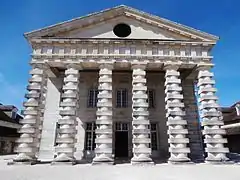 Portique couronné d'un fronton à jour dont le tympan est percé d'un œil-de-bœuf (saline royale d'Arc-et-Senans).