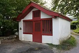Vue d’un petit oratoire, maisonnette aux murs blancs et aux boiseries rouge sang.