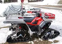 Véhicule tout-terrain (VTT) dont les roues sont remplacées par des chenilles.