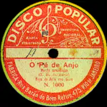 Photographie en couleur du centre d'un disque 78 tours. Le centre est représenté par un disque principalement orange avec un pourtour jaune. Il y est notamment écrit le titre de la chanson et le nom du label discographique, Disco Popular.