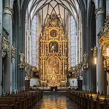 Photographie d'une vaste nef d'église, à voûte sur croisée d'ogives, présentant un décor baroque