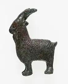 Photographie d'une statuette de bélier en bronze, de profil, de couleur marron-vert.