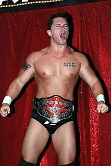 Un catcheur torse nu portant une ceinture de champion de catch.