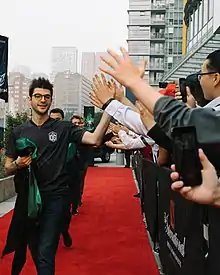 Une équipe de joueurs de jeu vidéo arrive sur un tapis rouge et tape dans la main de spectateurs.