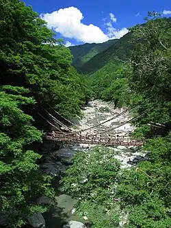 Pont de corde Kazura traversant une rivière dans la vallée.