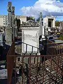 Photographie en couleurs d'une stèle funéraire de type chapelle au milieu d'un cimetière.