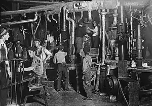 Une vieille photo en noir et blanc montre une douzaine d'enfants et d'adultes travaillant dans une usine.