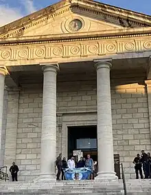 Photographie en couleurs représentant un groupe de personnes sur le perron du tribunal de Pau.