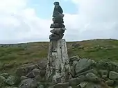 Photographie du sommet rocheux d'une colline, sur lequel est construite une borne.
