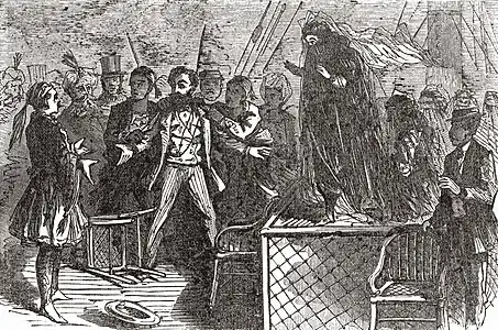 Gravure, Greenwood écartant les bras devant une table sur laquelle se tient une femme voilée.